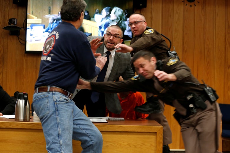 Randall Margraves (L) lunges at Larry Nassar (wearing orange), a former team USA Gymnastics doctor who pleaded guilty in November 2017 to sexual assault charges, during victim statements of his sentencing in the Eaton County Circuit Court in Charlotte, Michigan on February 2, 2018.